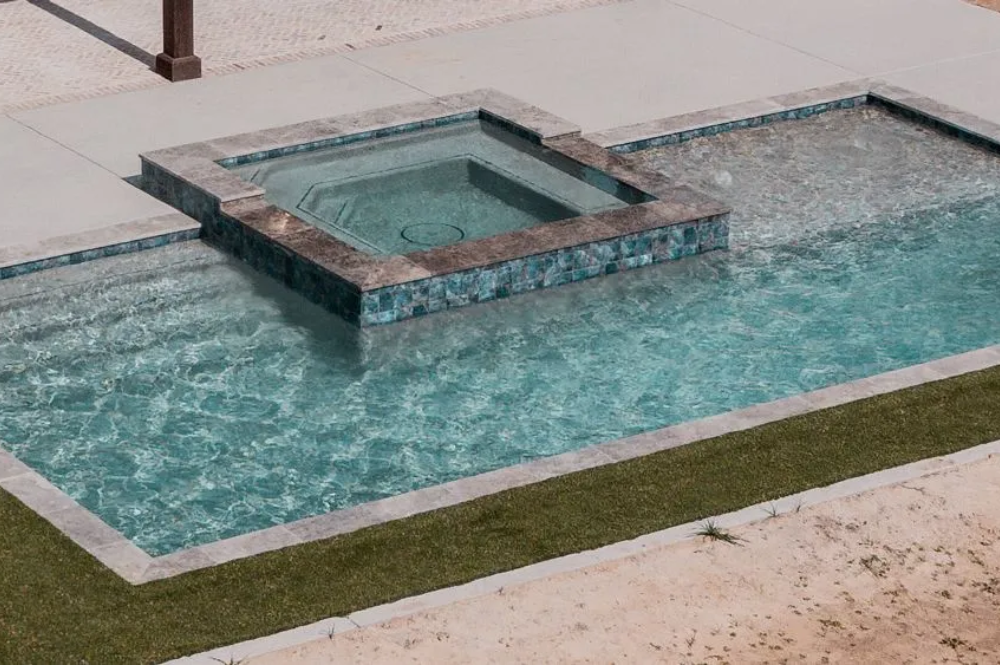 Aerial-view-of-a-modern-swimming-pool-and-spa-featuring-clear-blue-water-stone-borders-and-surrounding-concrete-pavement-and-grass Aerial view of a modern swimming pool and spa, featuring clear blue water, stone borders, and surrounding concrete pavement and grass