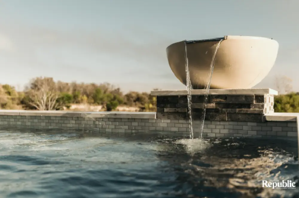 Aerial view of a modern, two-section swimming pool with crystal-clear water, featuring a raised hot tub area. Surrounding concrete and grass Aerial view of a modern, two-section swimming pool with crystal-clear water, featuring a raised hot tub area. Surrounding concrete and grass